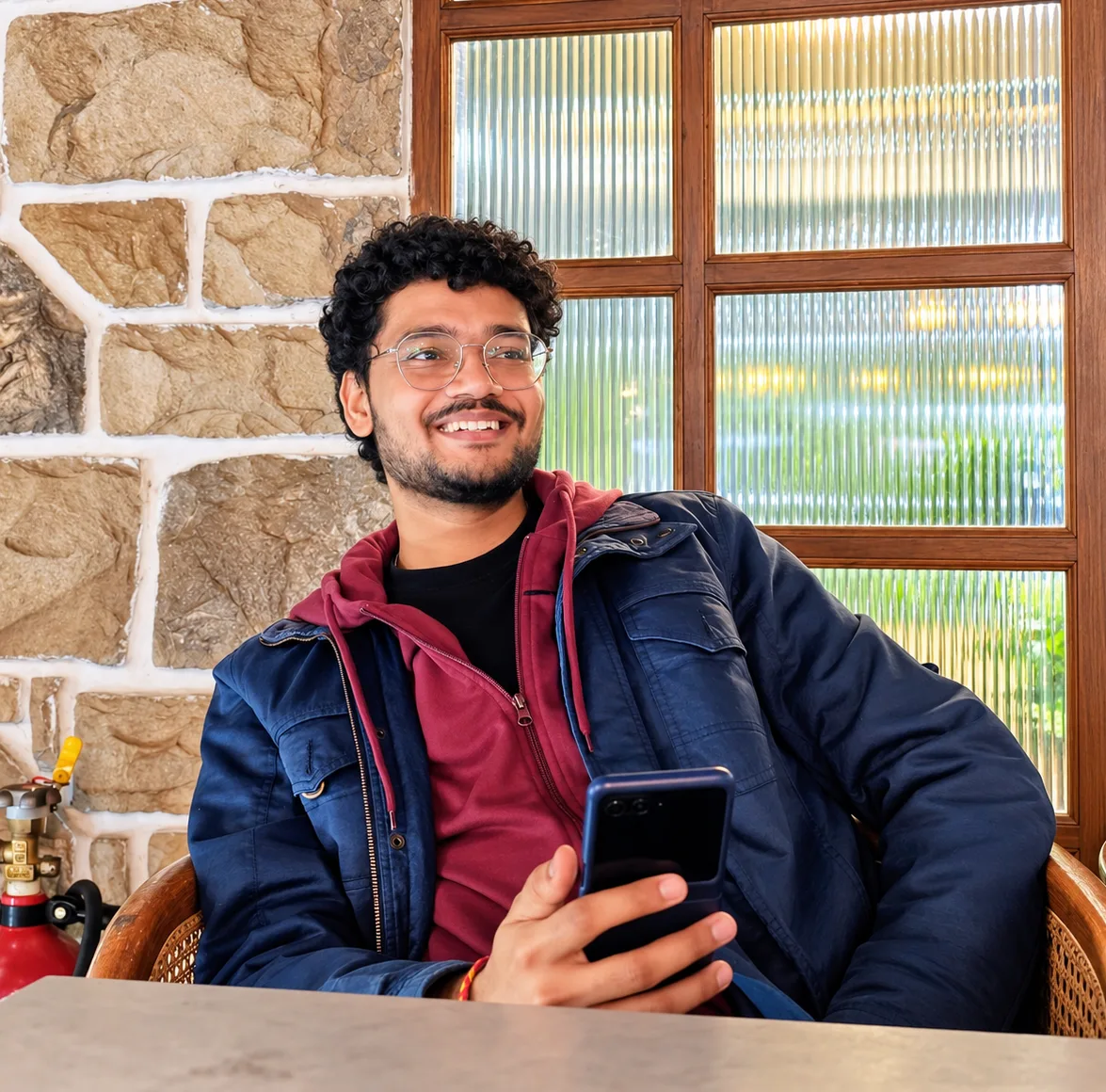 Aviral Bajpai smiling at a café table, holding his phone